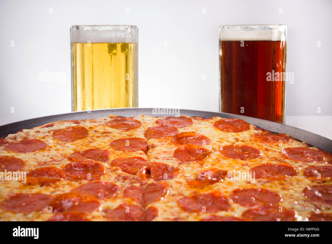 Pizza au pepperoni et la lumière et l'obscurité de la bière dans une plaque d'argent Banque D'Images