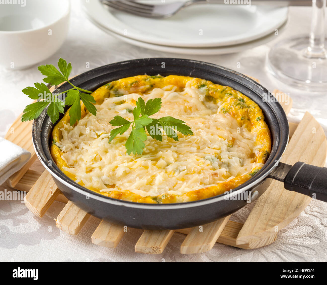 Frittata à la ricotta italienne, cheddar, gruyère et parmesan dans une poêle sur une table. Banque D'Images