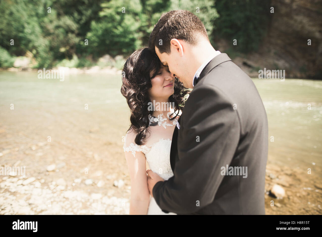 Beau couple de mariage et l'adoption de près de la rive d'une rivière de montagne avec des pierres Banque D'Images