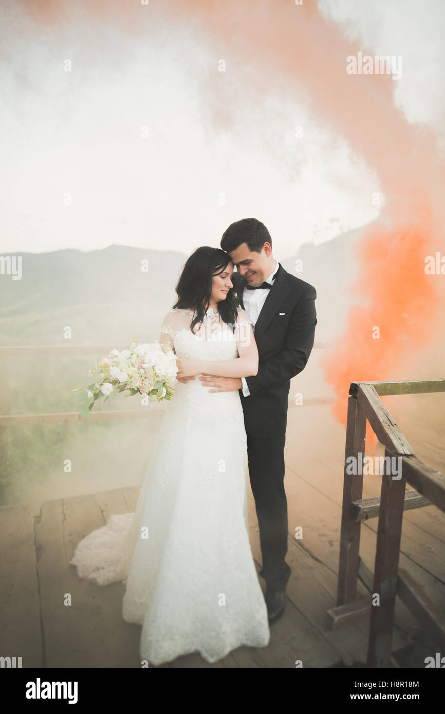 Couple de mariage à proximité de rochers avec la fumée de couleur derrière eux Banque D'Images