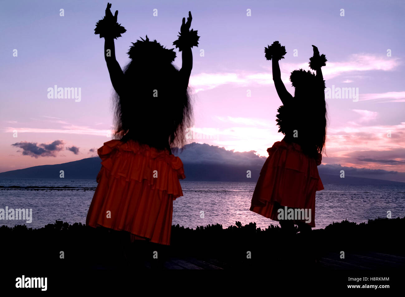 Maui, Hawaï, États-Unis. Deux femmes interprétant la danse hula hawaïenne traditionnelle au coucher du soleil sur la plage, face à l'océan Pacifique. Banque D'Images