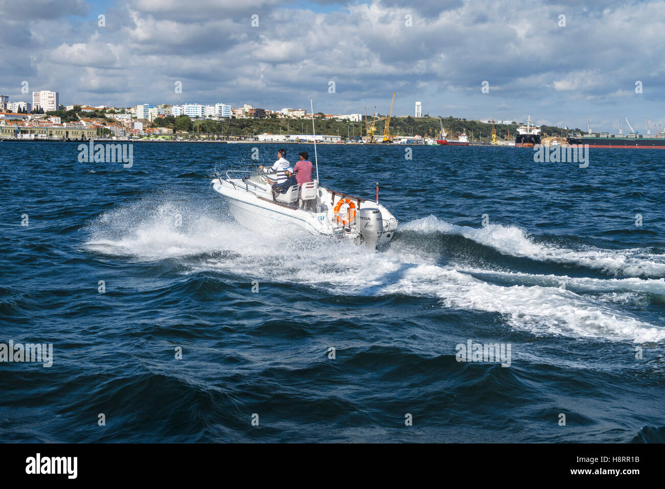 Petit bateau à moteur traversant une rivière avec trois personnes Banque D'Images Petit bateau à moteur traversant une rivière avec trois personnes Banque D'Images
