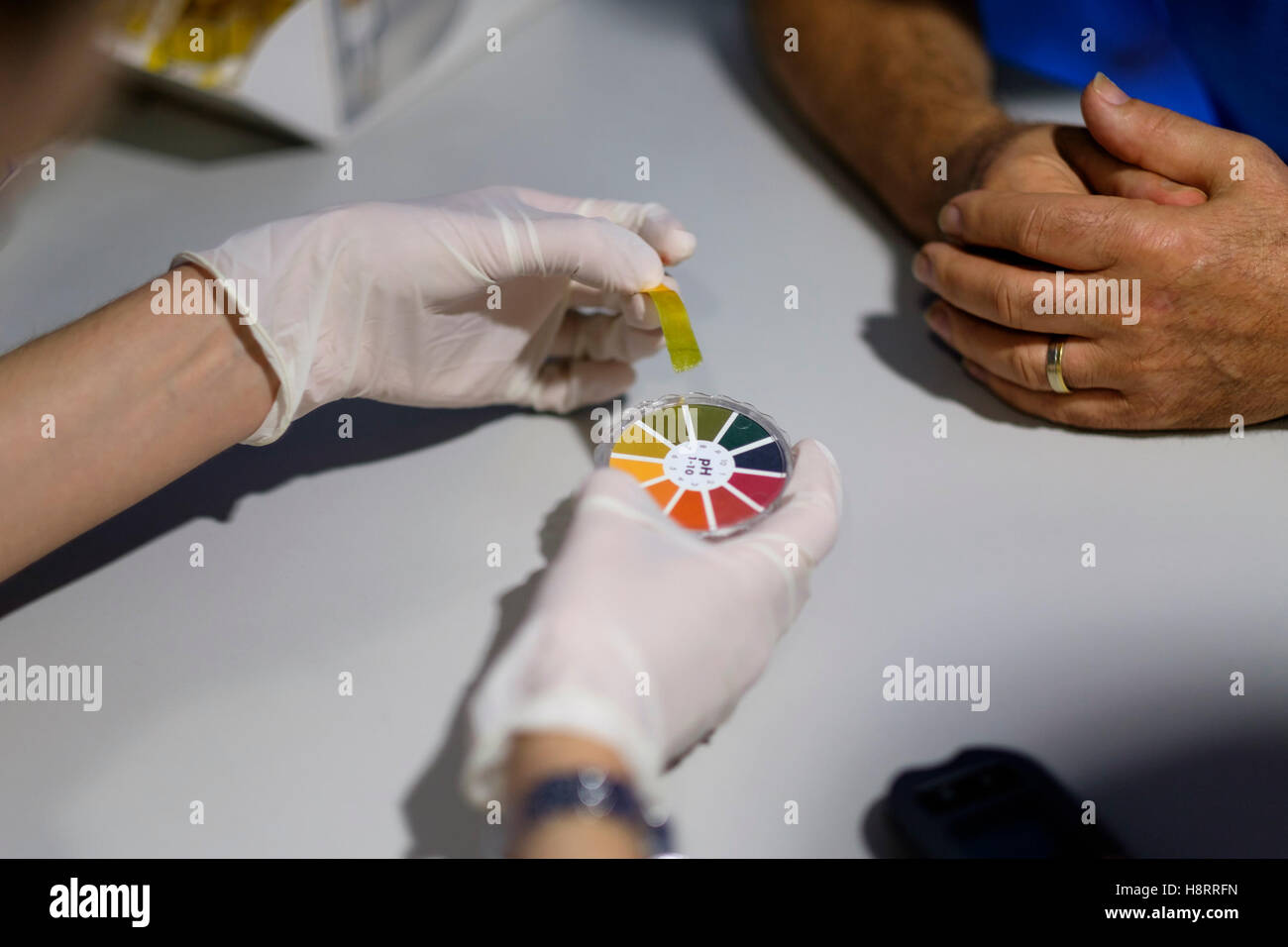 Travailleur de la santé à l'aide d'une échelle de pH mètre à un test de la salive du patient ou de l'Alcalinité Acidité Banque D'Images