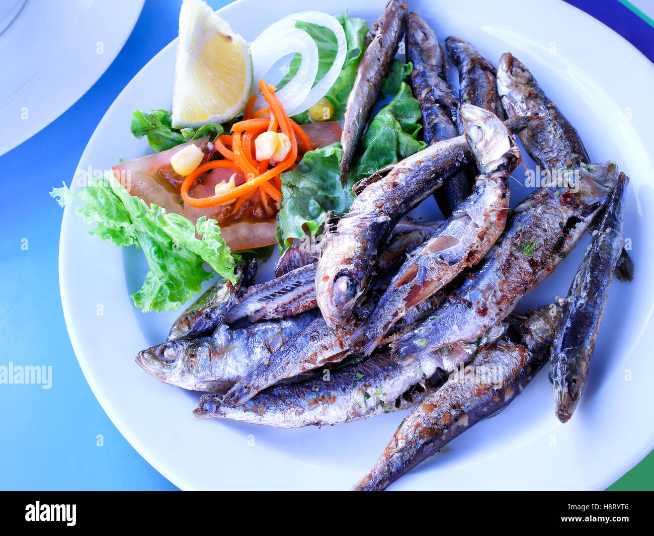Assiette de sardines grillées servies avec salade, tomate, oignon et tranche de citron Banque D'Images