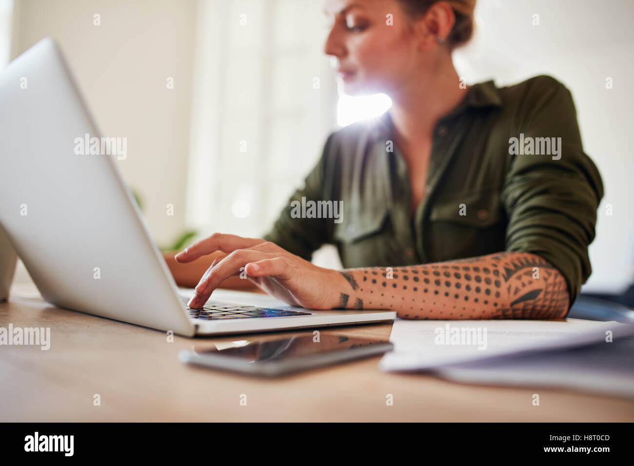 Shot of woman working on laptop at home. Femme assise à table avec les mains sur clavier d'ordinateur portable. Banque D'Images
