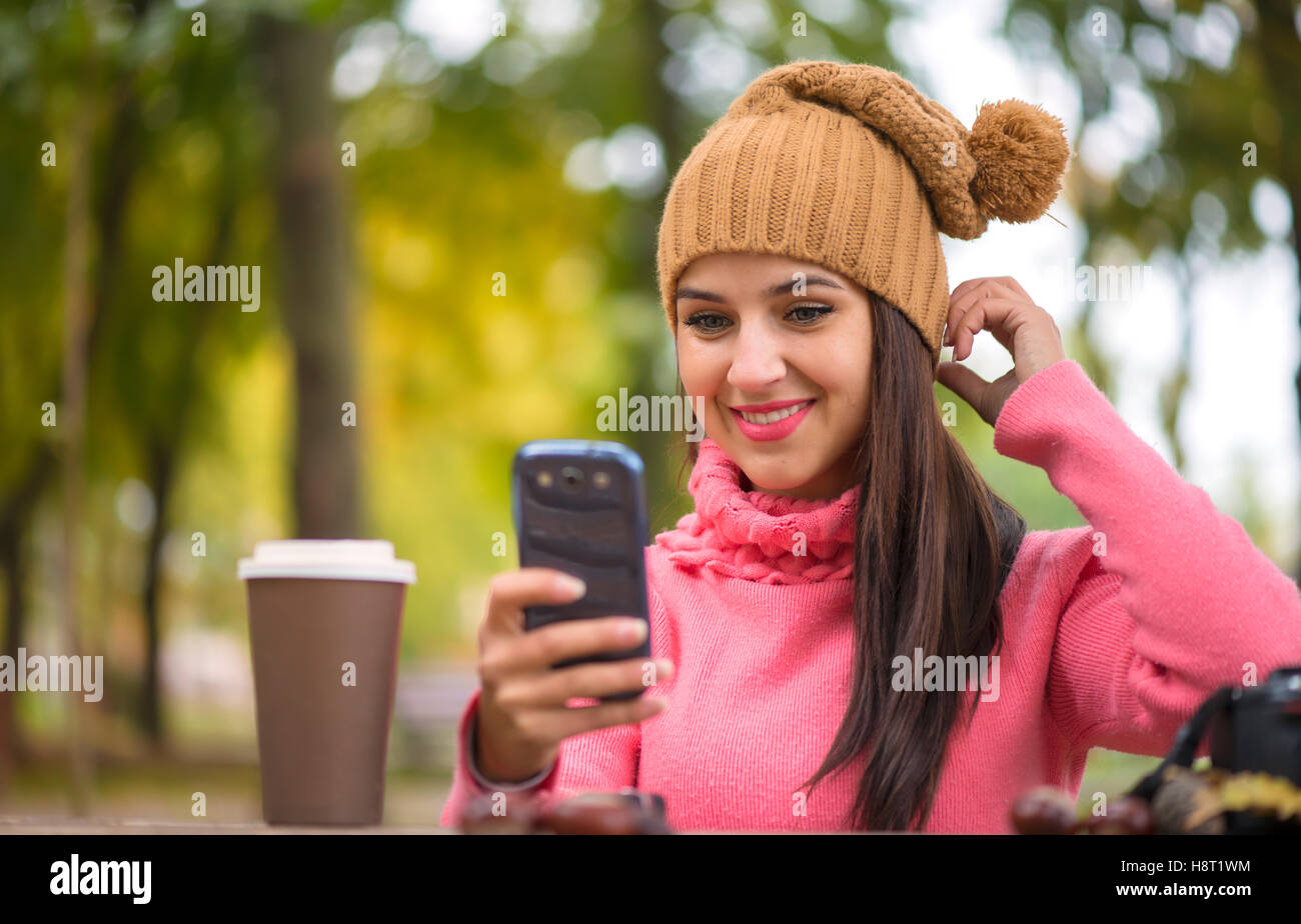 Technologie Internet et de bonheur concept. Femme heureuse girl taking self photo smartphone selfies avec appareil photo à l'extérieur à l'automne Banque D'Images