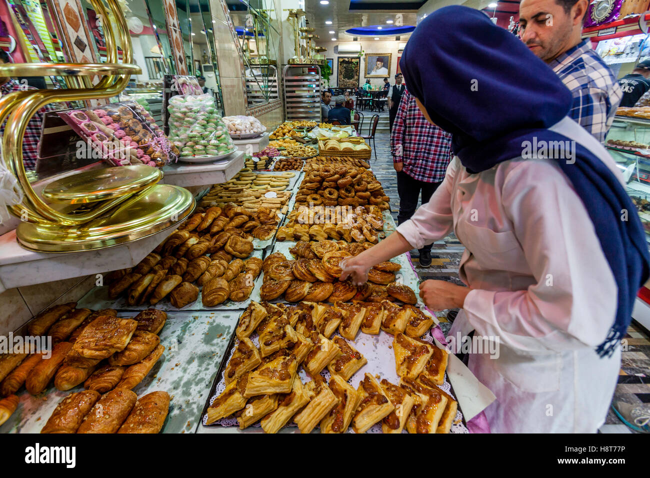 Un travailleur féminin sélectionne les pâtisseries de l'affichage au Dallas Patisserie, Tétouan, Maroc Banque D'Images