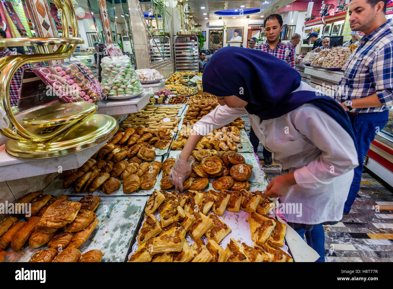 Un travailleur féminin sélectionne les pâtisseries de l'affichage au Dallas Patisserie, Tétouan, Maroc Banque D'Images
