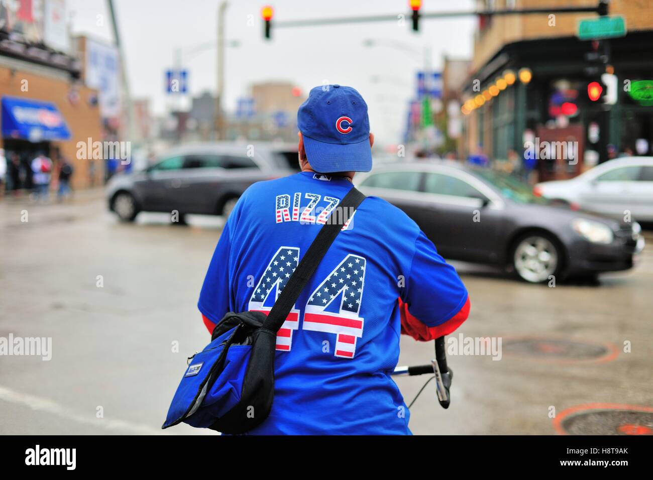 Un cycliste en tenue des Cubs de Chicago s'arrête à un feu rouge à l'intersection à Wrigley Field. Chicago, Illinois, USA. Banque D'Images