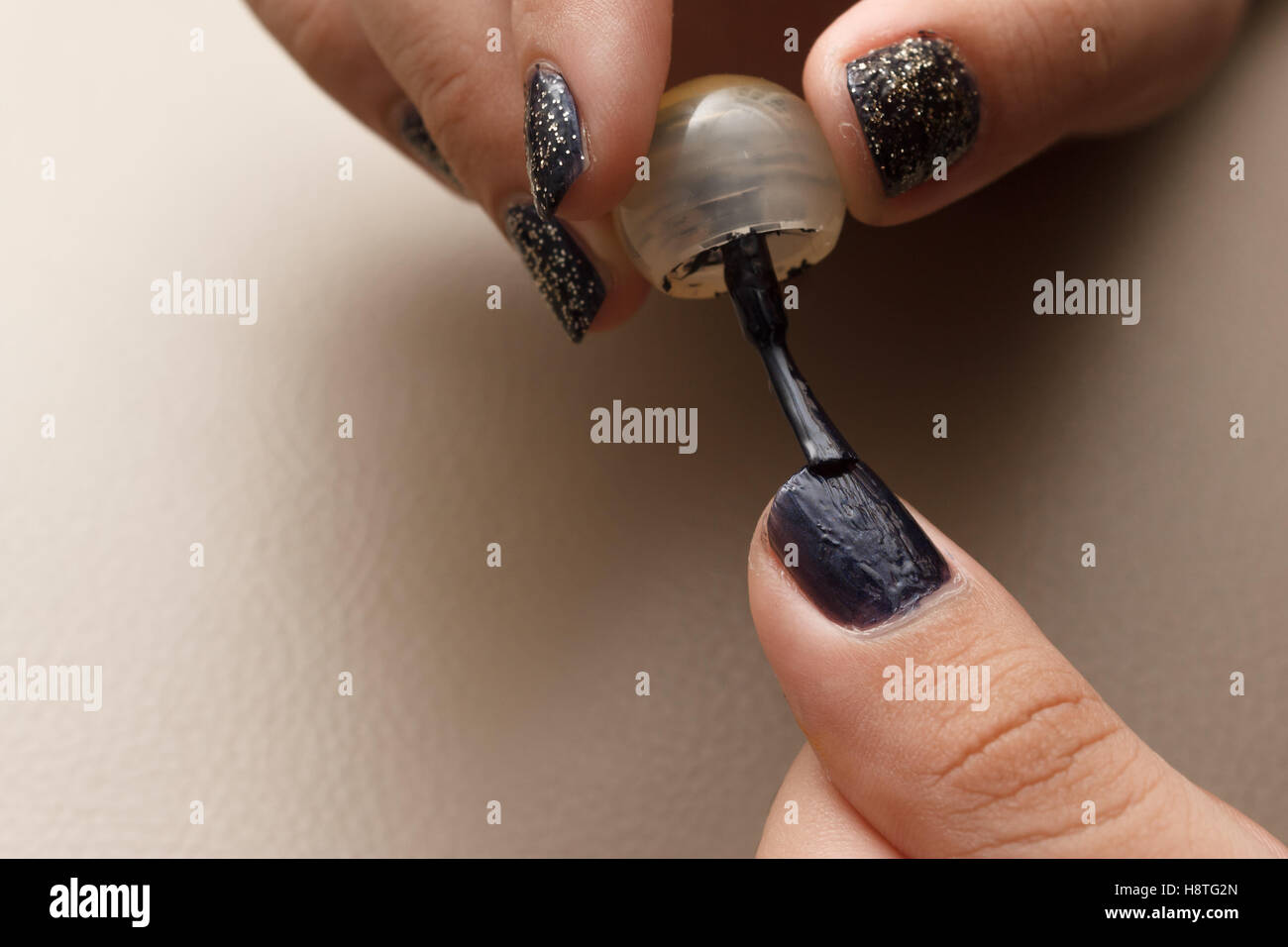 Quelqu'un d'appliquer délicatement le vernis à ongles de couleur noire à l'aide d'un pinceau pour faire un très beau nail art. Banque D'Images