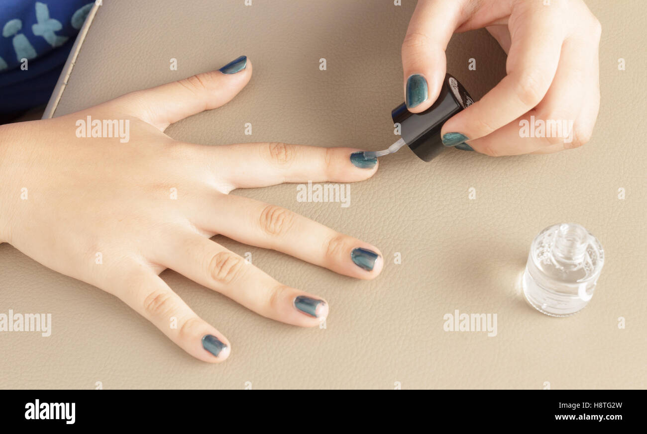 Quelqu'un d'appliquer doucement la couleur transparente à l'aide d'une brosse à ongles pour faire un très beau nail art. Banque D'Images