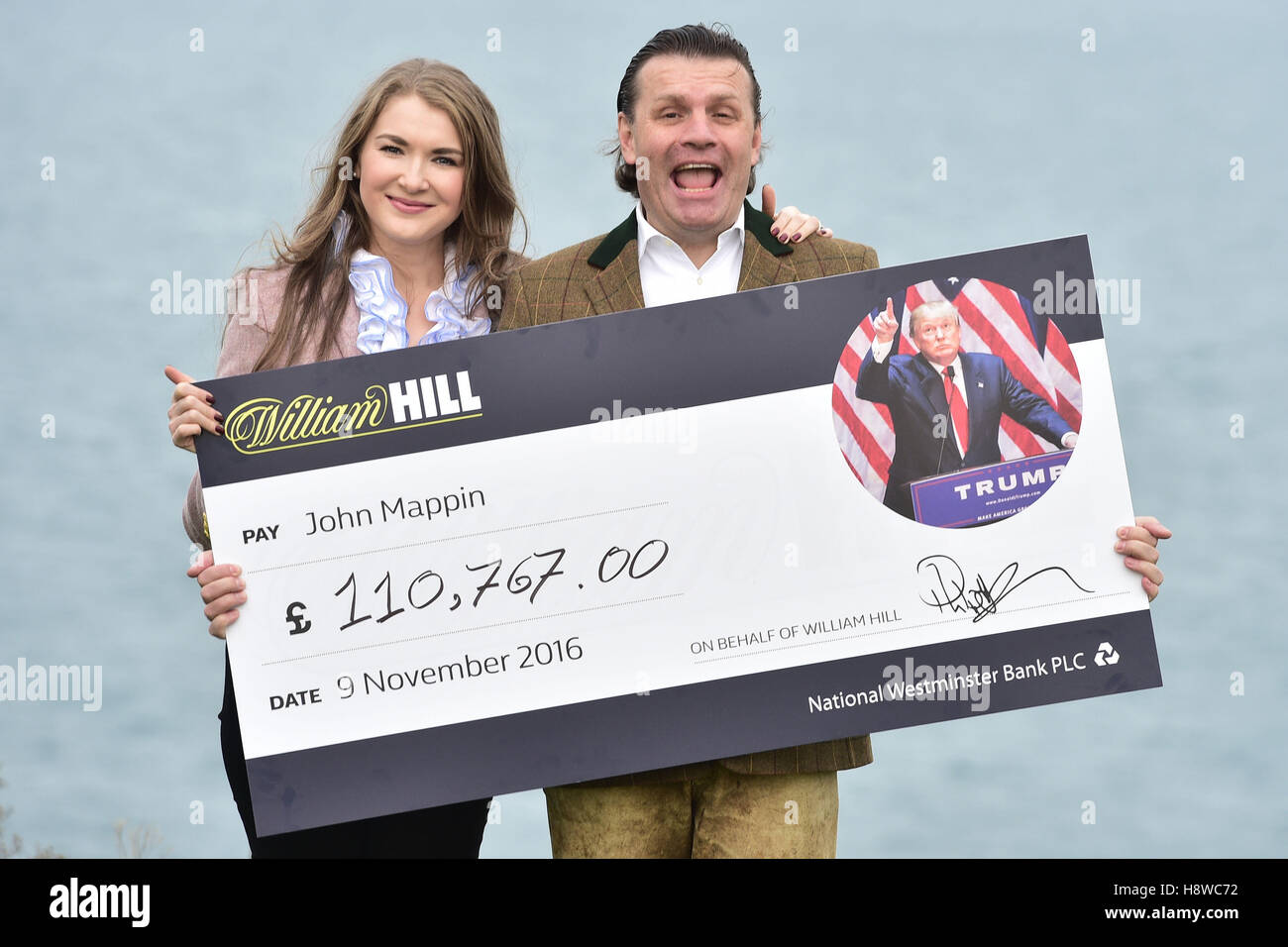 John Mappin, propriétaire de l'hôtel Camelot Castle à Tintagel, en Cornouailles, avec sa femme Irina et un chèque de £100,000 qu'il a reçu de William Hill après avoir mis une série de Paris sur Donald Trump devenant président des États-Unis. Banque D'Images
