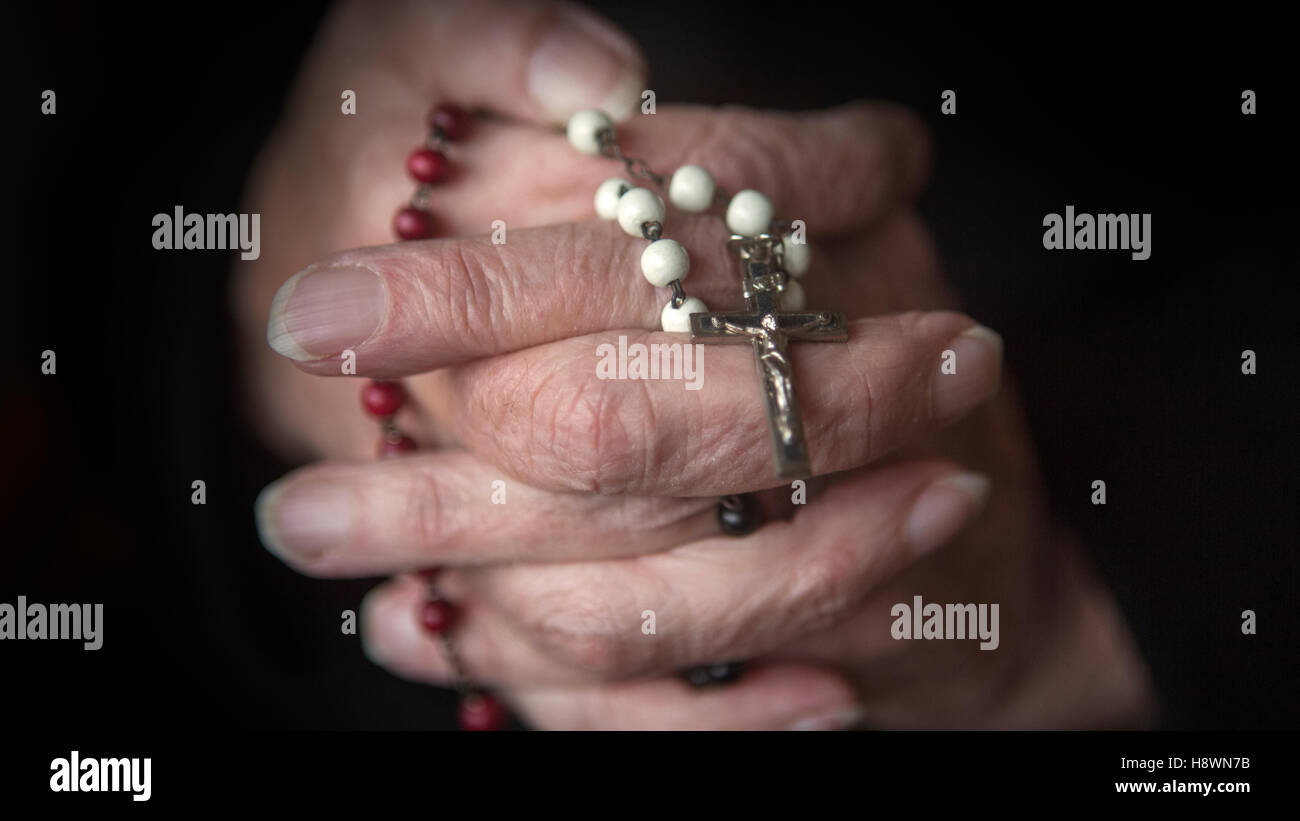 Vieille Femme mains priant et tenant un rosaire Banque D'Images