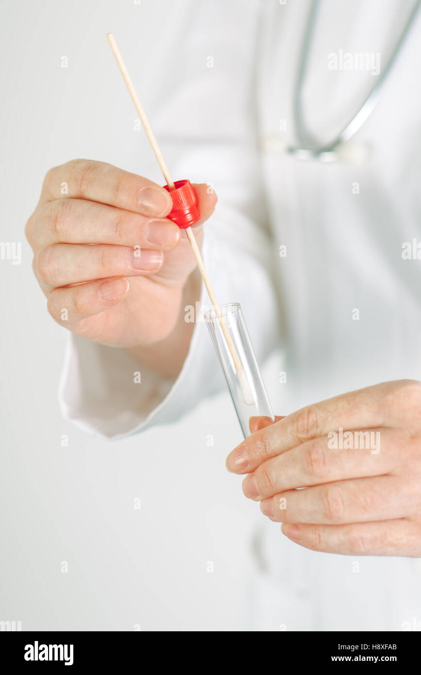 Spécialiste en médecine buccale holding femelle coton-tige et tube à essai, prêt à recueillir de l'ADN des cellules à l'intérieur de la joue d'une personne Banque D'Images