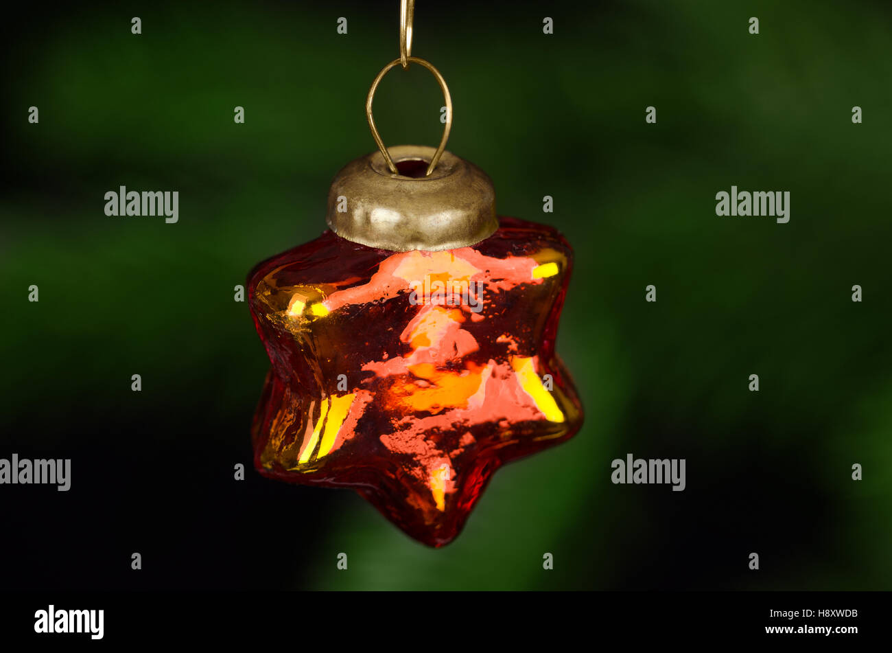 En verre rouge star décoration d'arbre de Noël. Boule de Noël en forme d'étoile à la main. Un petit arbre de Noël brillant et l'ornement. Banque D'Images