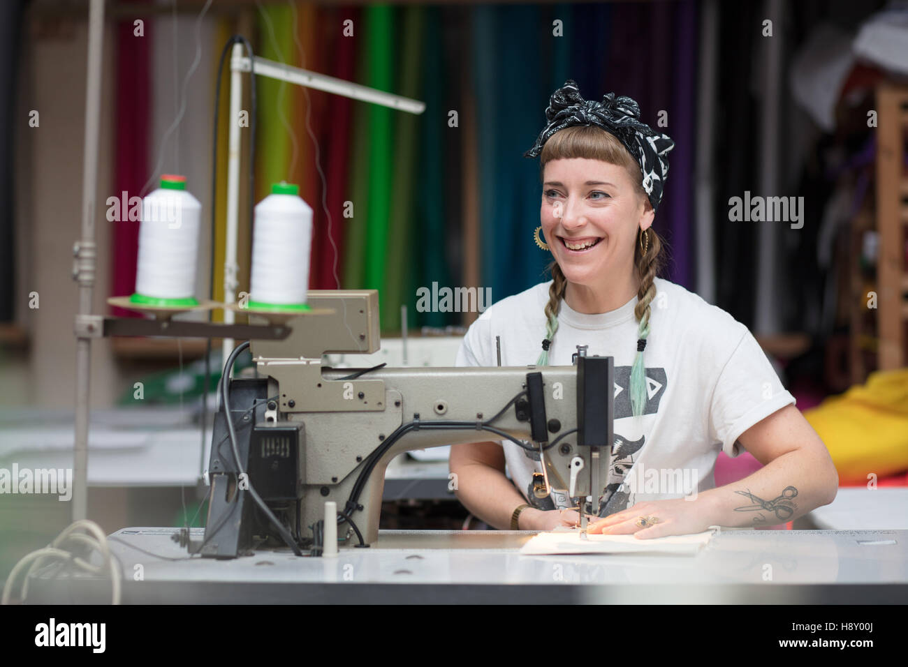 Jeune couturière tatouée dans un environnement d'usine de couture Banque D'Images
