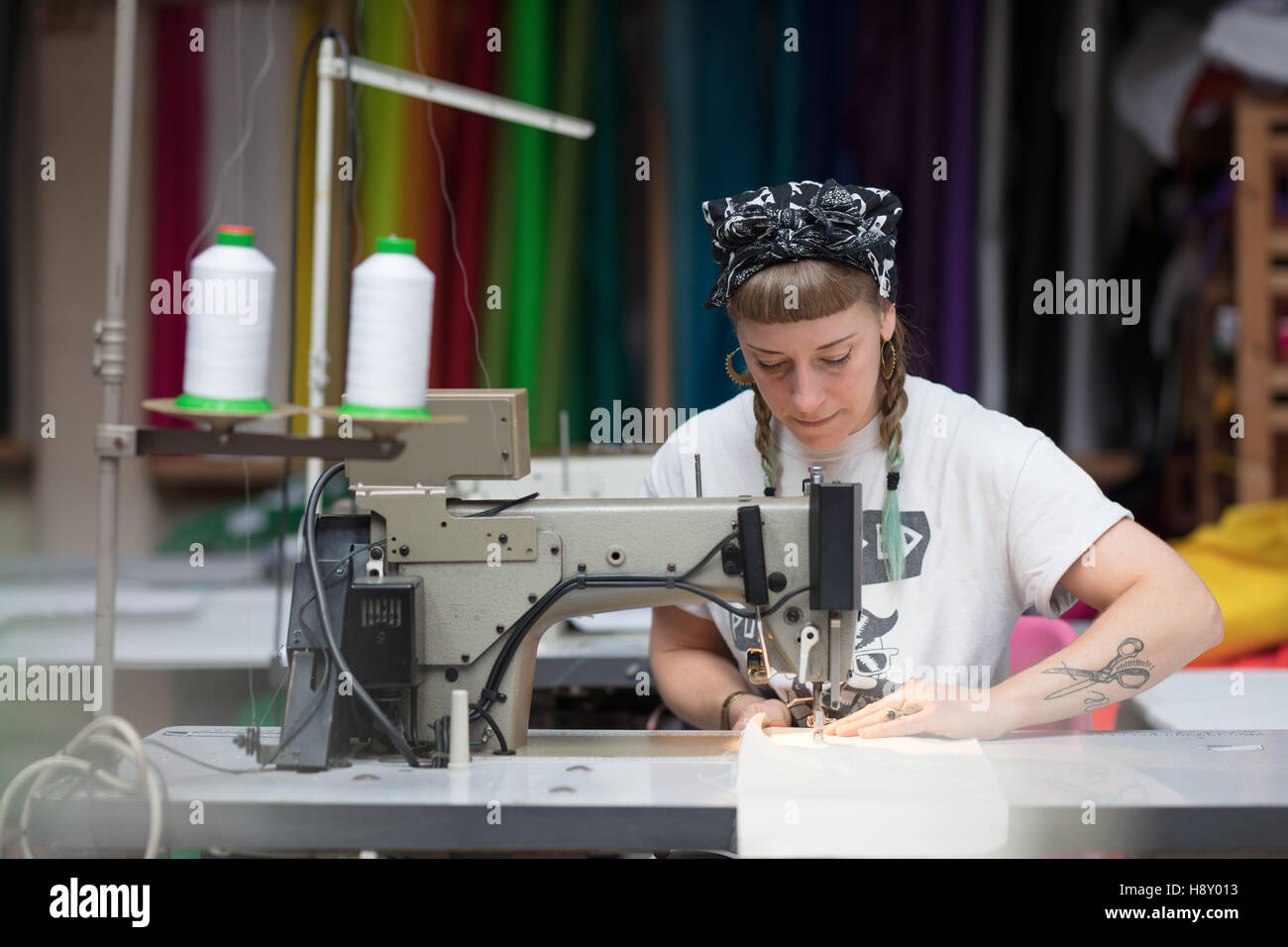 Jeune couturière tatouée dans un environnement d'usine de couture Banque D'Images