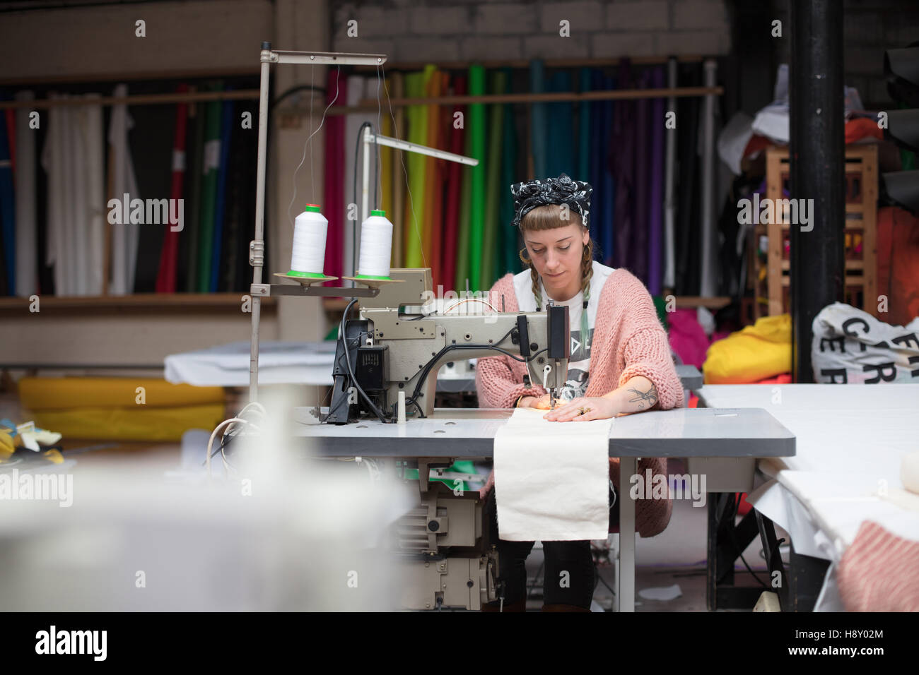 Jeune couturière tatouée dans un environnement d'usine de couture Banque D'Images