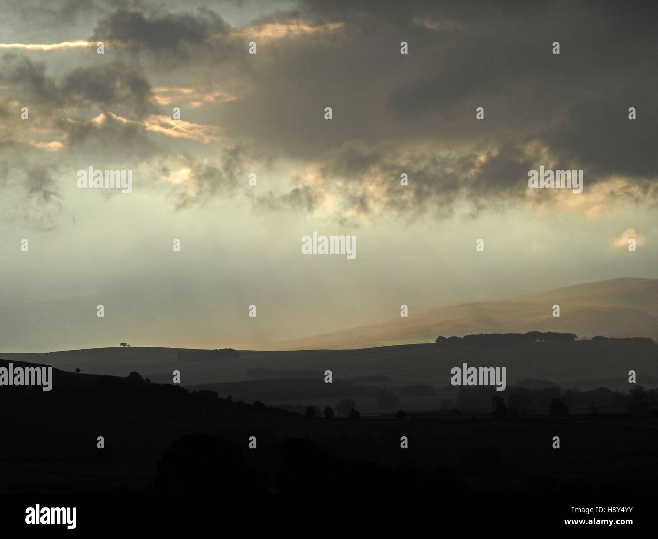 Moody golden morning light atmosphérique traversant des nuages sombres sur le recul de la Foothills England UK Cumbria Fells Cap Sud Banque D'Images