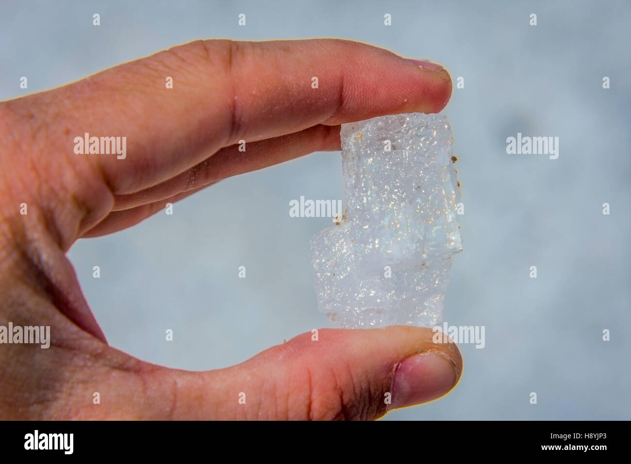 En cristal de sel gros dans la main contre le ciel bleu Banque D'Images