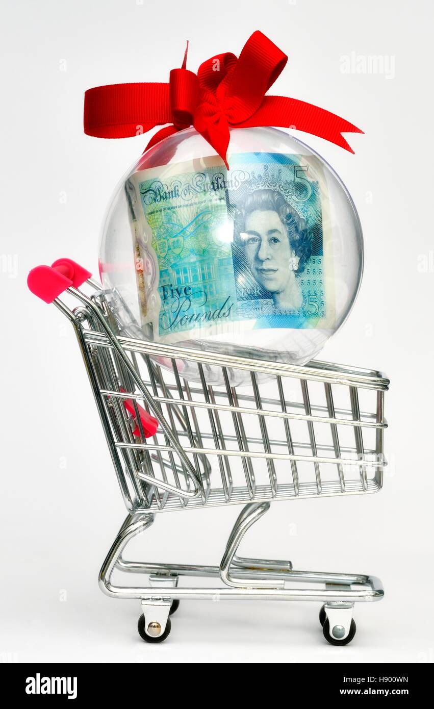 Une note de cinq livres dans une boule de Noël dans un panier. Banque D'Images