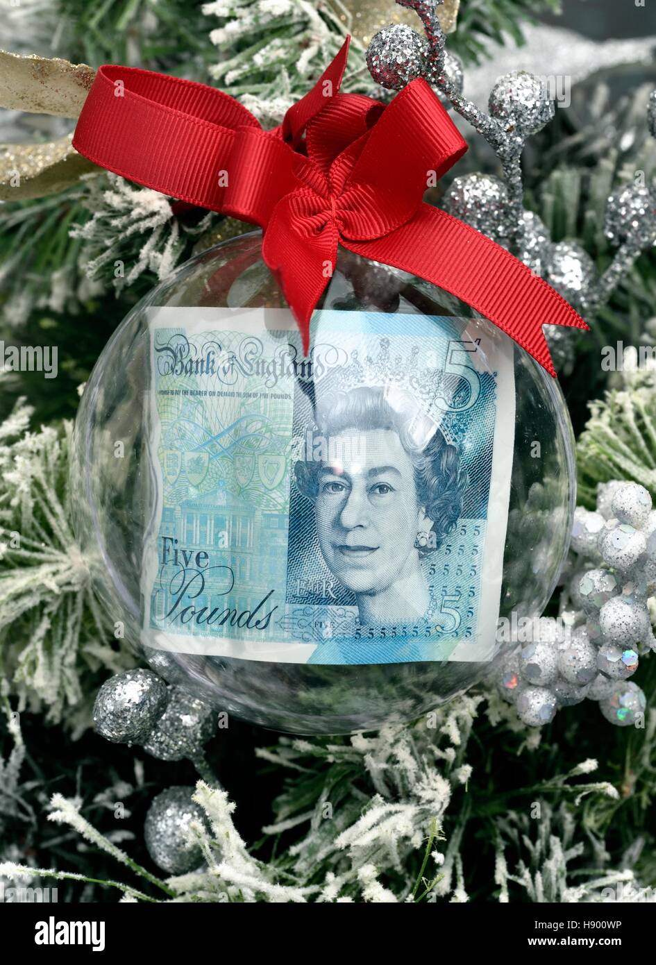 Une note de cinq livres dans une boule de noël sur un arbre. Banque D'Images