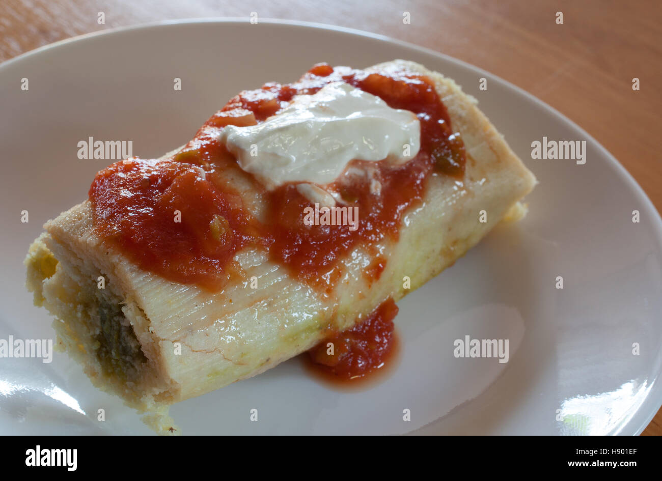 Tamale avec piment vert farce garnie de crème sure et salsa Banque D'Images