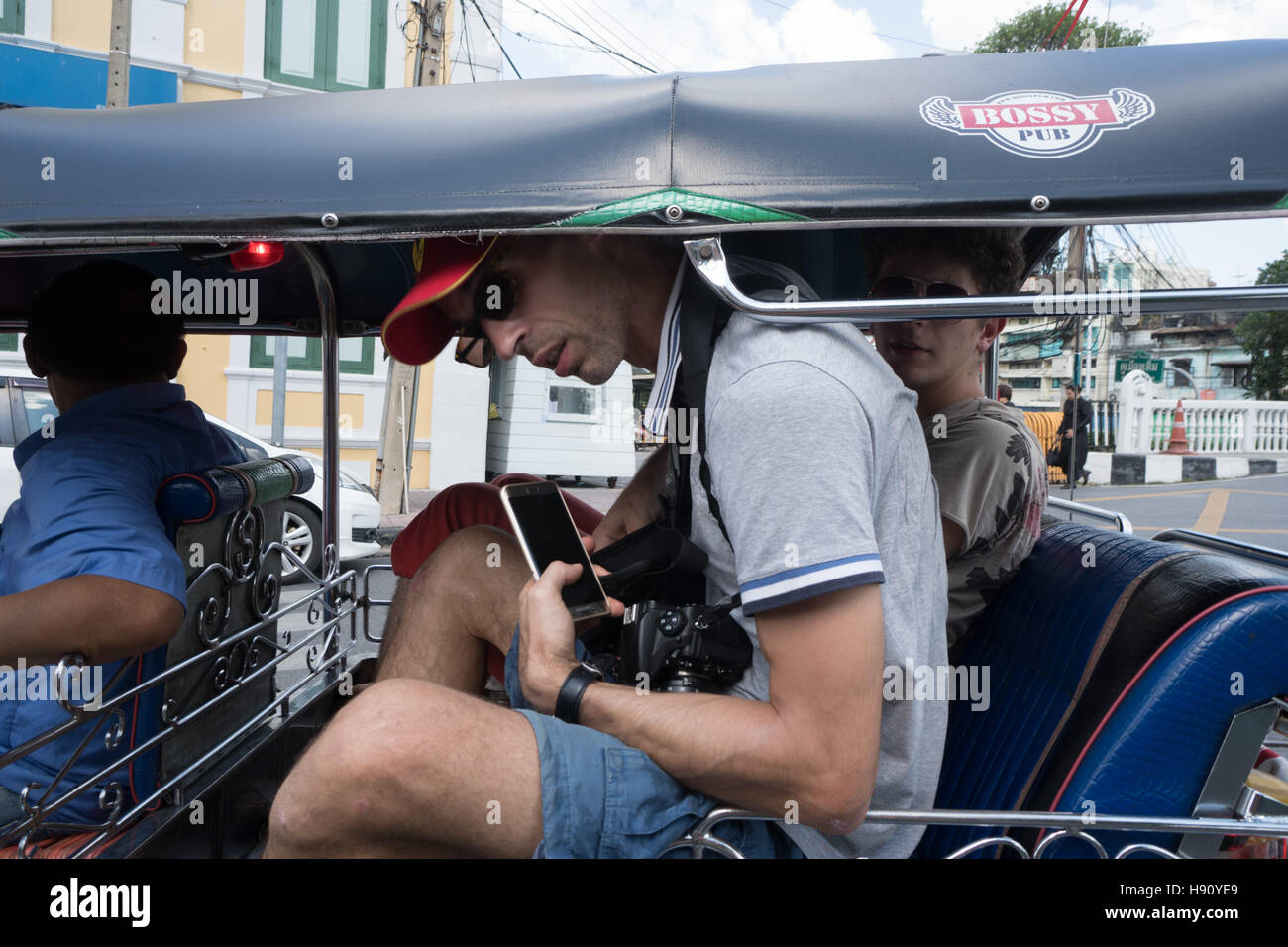 Deux passagers de sexe masculin les touristes et conducteur assis dans véhicule taxi - tuk-tuk, Bangkok, Thaïlande Banque D'Images