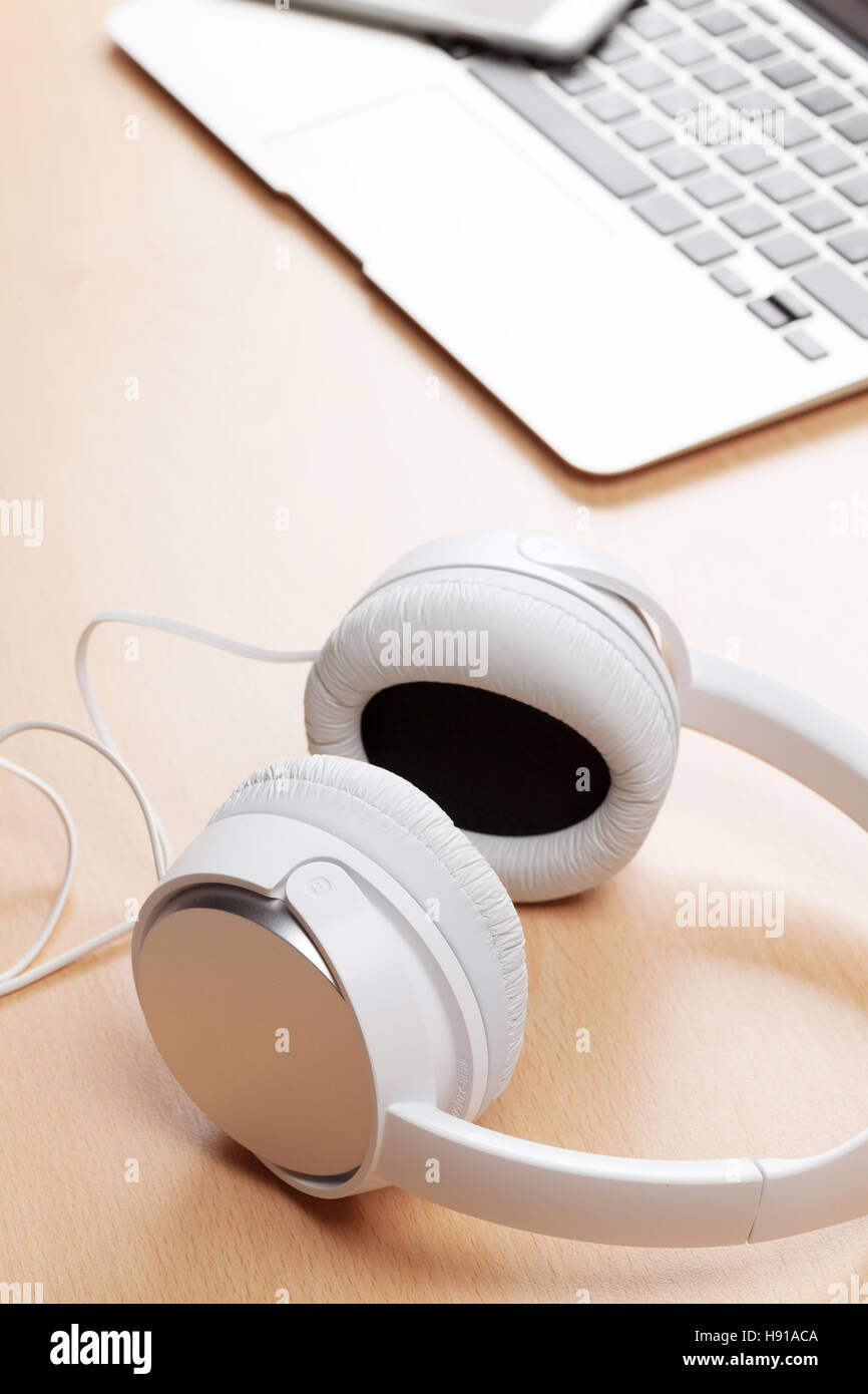 Des écouteurs et un ordinateur portable sur un bureau en bois table. Concept Musique Banque D'Images