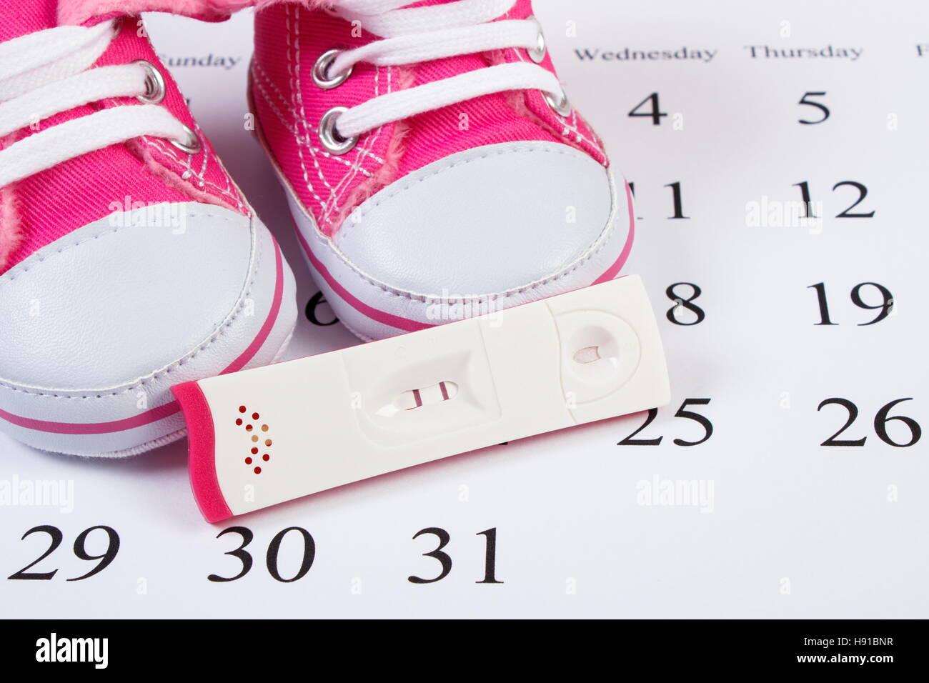 Test de grossesse avec résultat positif et les chaussons bébé couché sur le  calendrier, concept de l'extension de la famille et s'attendant pour bébé  Photo Stock - Alamy