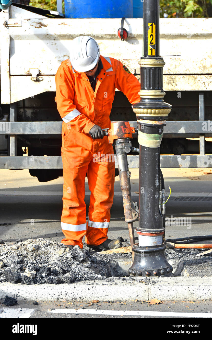 Workman travaillant sur route travaux de réparation marteau pneumatique pneumatique L'outil d'équipement se déforme autour de la lampe de rue après Londres Angleterre ROYAUME-UNI Banque D'Images