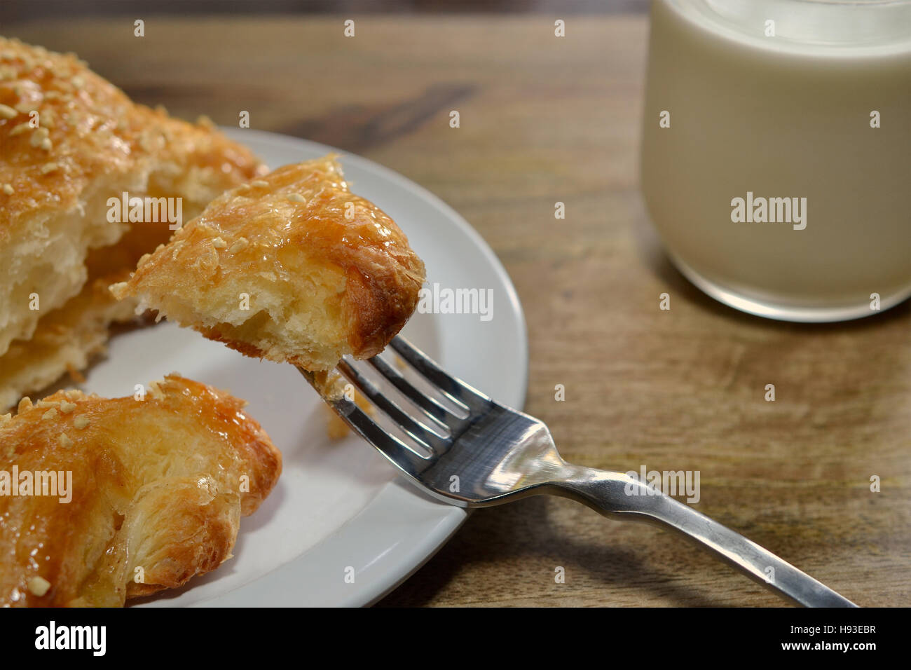 Gros plan sur un morceau de la pâtisserie autrichienne sur une fourchette, couverte de miettes d'amandes enrobées de sucre, et sur plaque blanche sur fond de bois, vu de Banque D'Images