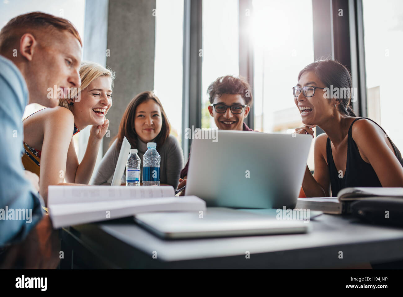 Happy friends using laptop assis à table de la bibliothèque. L'étude en groupe en bibliothèque universitaire. Banque D'Images