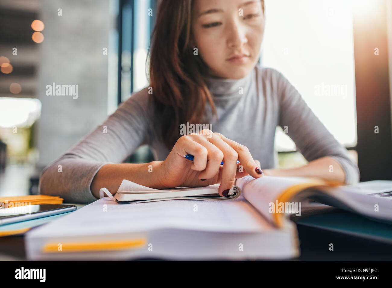 Close up image d'une jeune étudiante faisant des affectations dans la bibliothèque. Femme Asiatique la prise de notes à partir de manuels scolaires. Banque D'Images