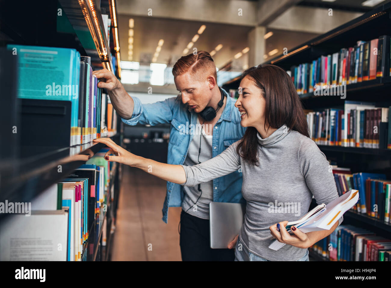 Deux jeunes étudiants obtenant des livres sur une étagère de bibliothèque publique. étudiants universitaires à la bibliothèque à la recherche d'informations pour leurs études. Banque D'Images