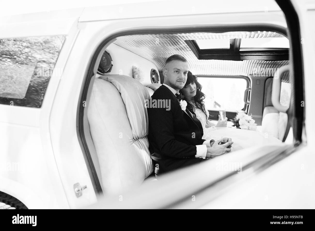 Couple de mariage élégance étonnante à l'intérieur limousine à leur magnifique journée de mariage. Photo en noir et blanc Banque D'Images