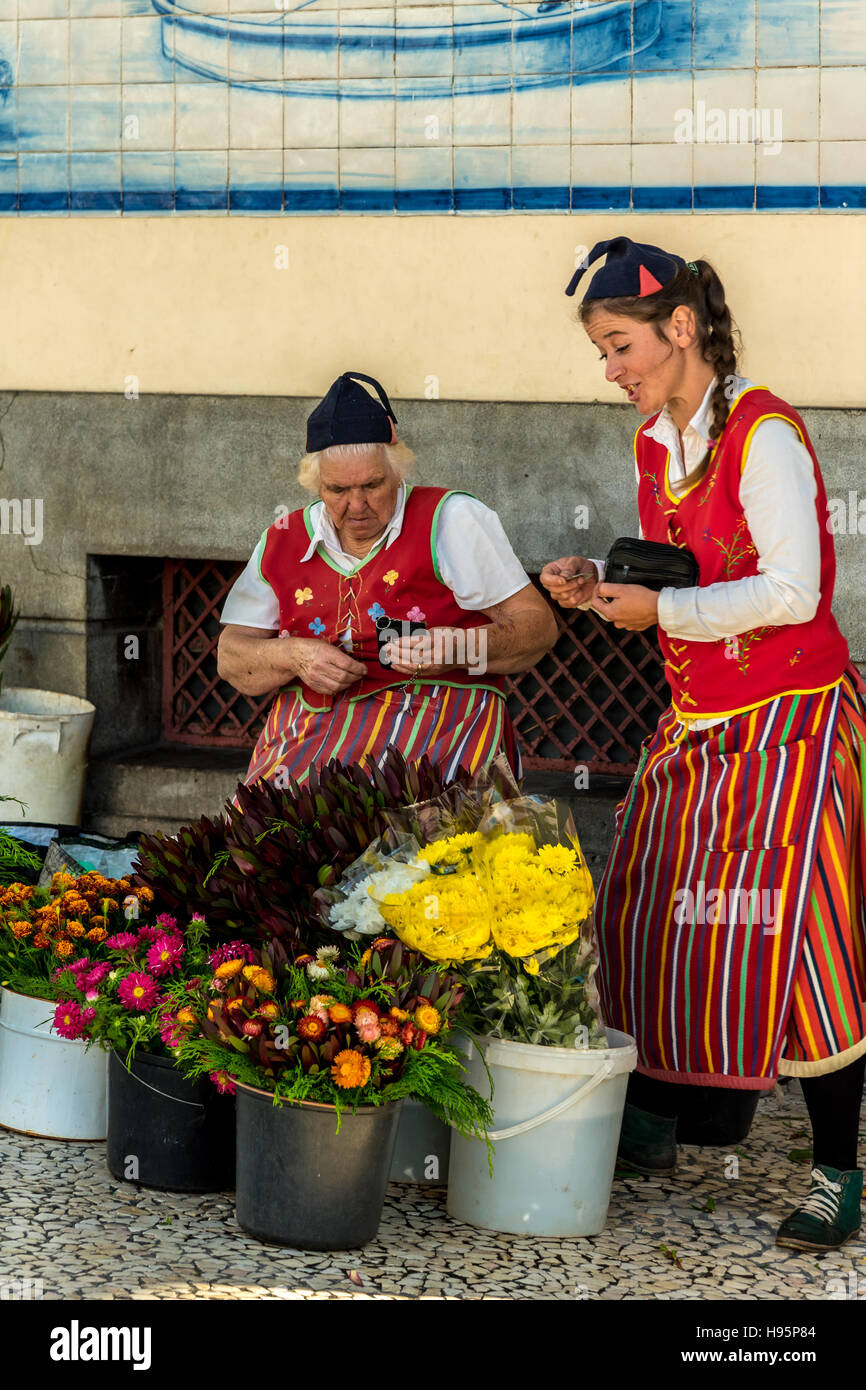 Les vendeurs de fleurs en costume traditionnel de Madère Funchal au marché avec des fleurs tropicales colorées Banque D'Images