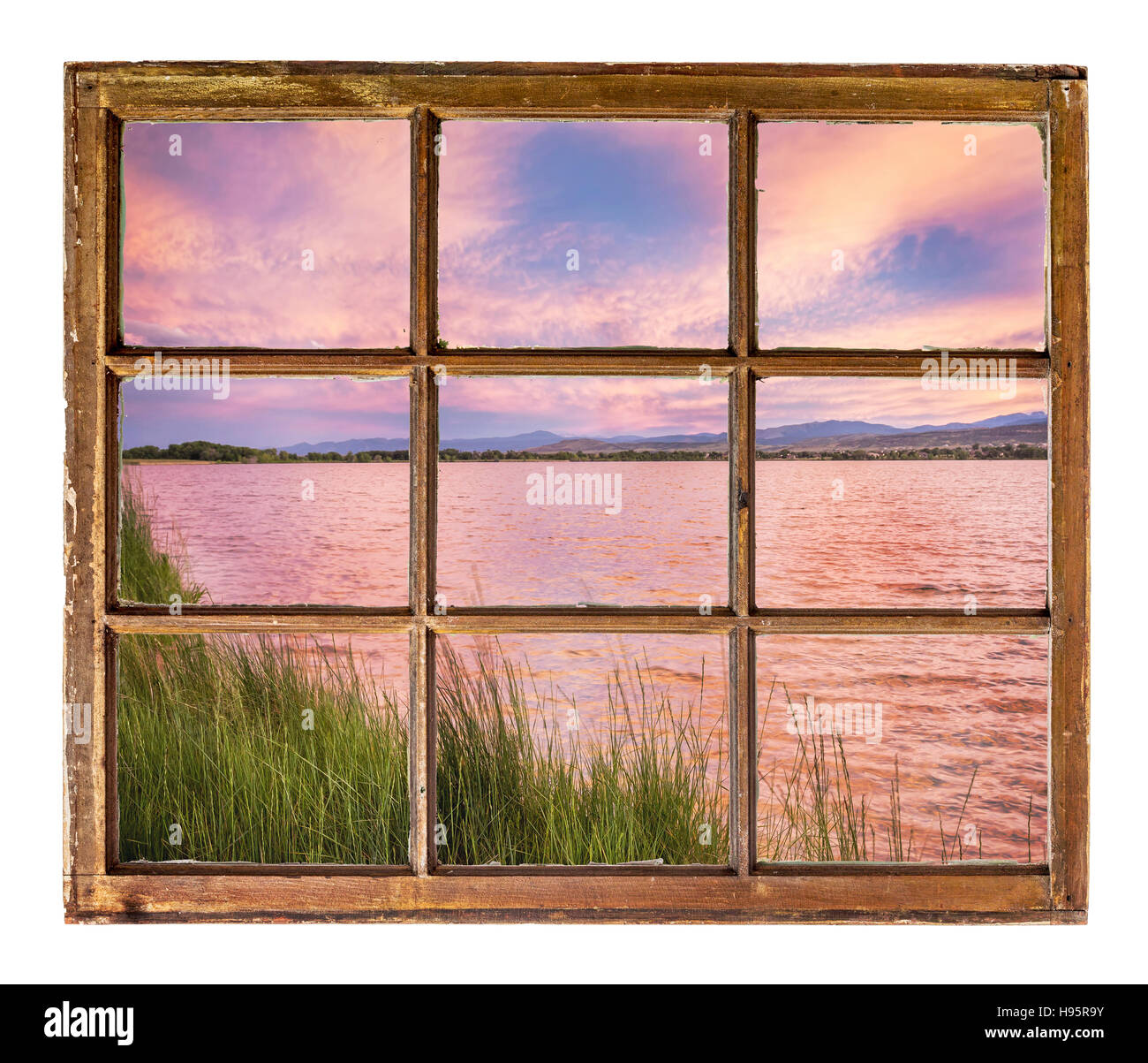 Coucher de soleil sur un lac avec des Montagnes Rocheuses en arrière-plan comme vu à partir d'une fenêtre à guillotine d'un vieux chalet Banque D'Images