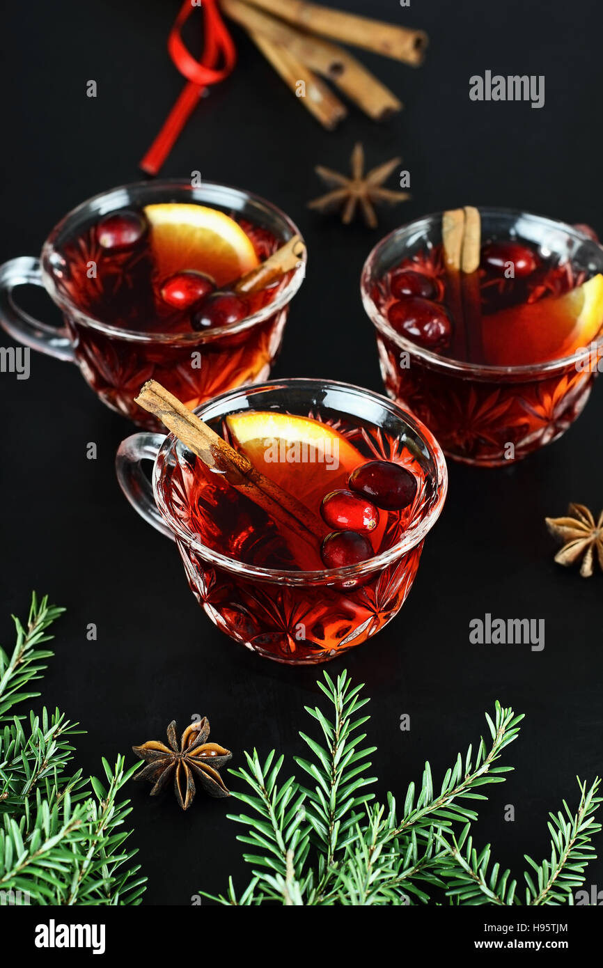 Punch de Noël rouge / verre avec de la cannelle, des tranches d'orange, l'anis et de canneberges fraîches sur un fond sombre. Banque D'Images