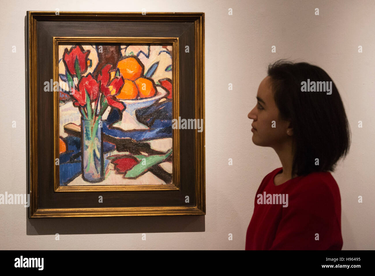 Londres, Royaume-Uni. 18 novembre 2016. Un employé de Sotheby's se penche sur la peinture Nature morte avec des tulipes et des oranges par Samuel John Peploe, est. GBP 250,000-350,000. Sotheby's présente un aperçu de leur vendre de l'Art écossais dans leur nouveau Bond Street locaux. La vente aux enchères aura lieu le 22 novembre 2016 à Londres. Banque D'Images