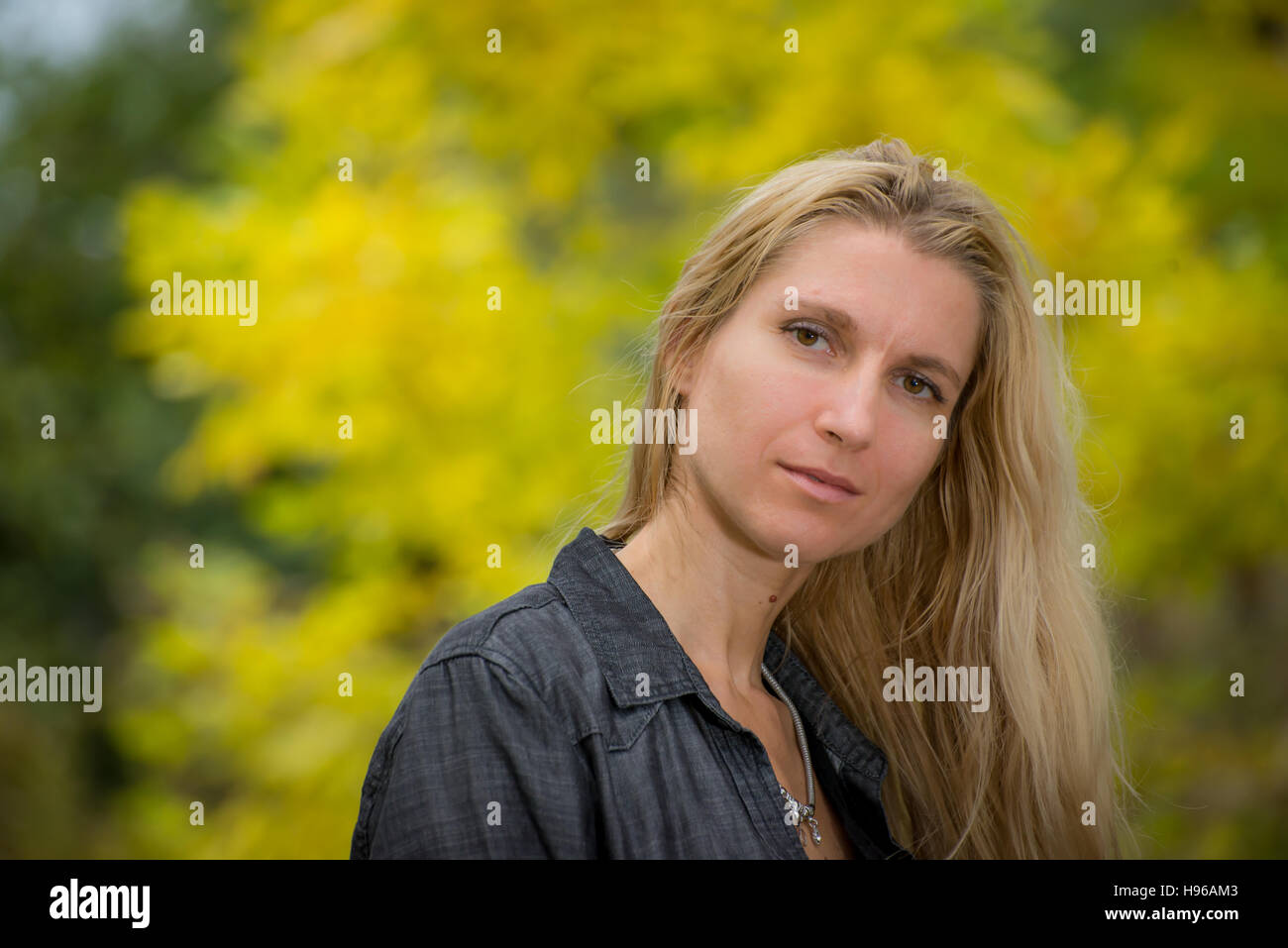 Jolie jeune femme blonde dans un parc avec arrière-plan flou Banque D'Images