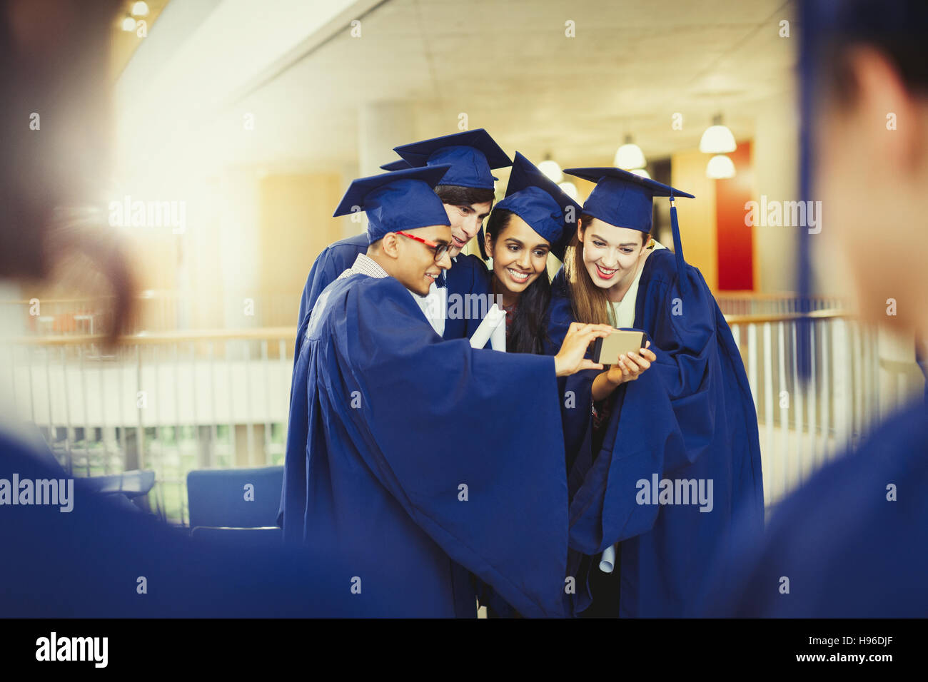 Les diplômés du collégial en cap and gown selfies en tenant Banque D'Images