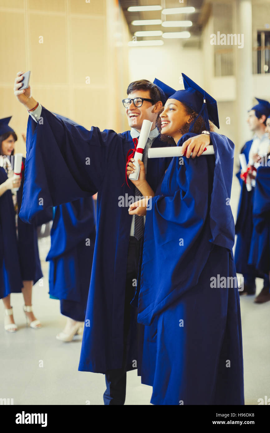 Les diplômés du collégial en cap et une blouse avec des diplômes en tenant selfies Banque D'Images