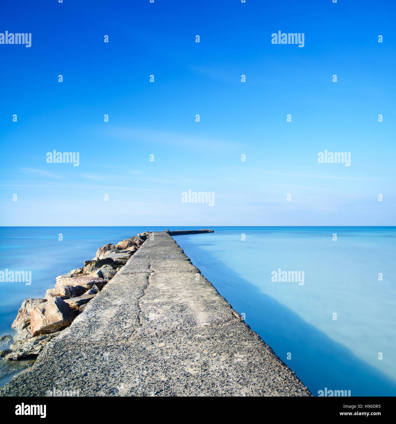 Les Roches et Béton pier ou jetée sur un océan bleu de l'eau. Photos à longue exposition Banque D'Images