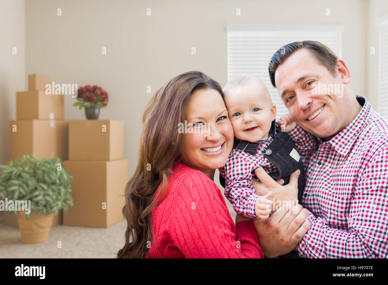 Happy Caucasian Family avec bébé dans la chambre avec des cartons. Banque D'Images