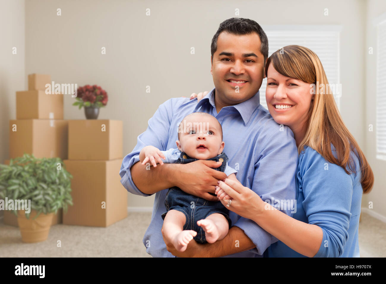 Happy Mixed Race Family avec bébé dans la chambre avec des paniers-Moving Boxes. Banque D'Images