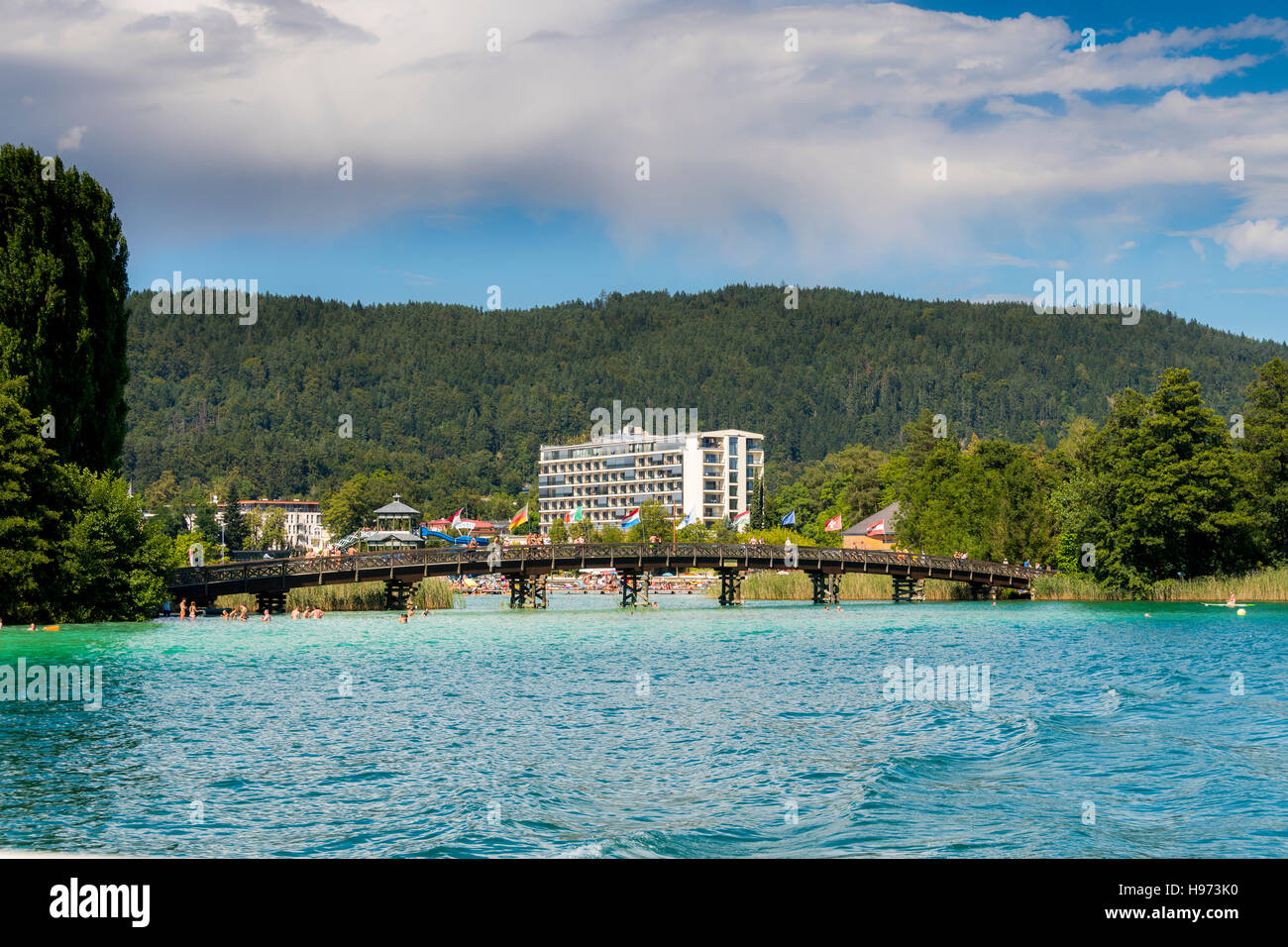 Portschach, Autriche - le 14 août 2016 : drapeaux internationaux volant au-dessus de la rambarde d'un pont menant de Portschach au Blumeninsel Banque D'Images