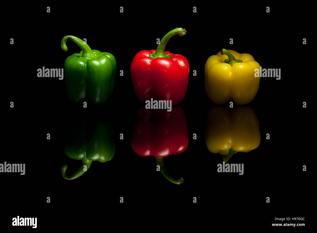 Trois ensemble les poivrons rouge vert jaune isolé sur fond réfléchissant noir Banque D'Images
