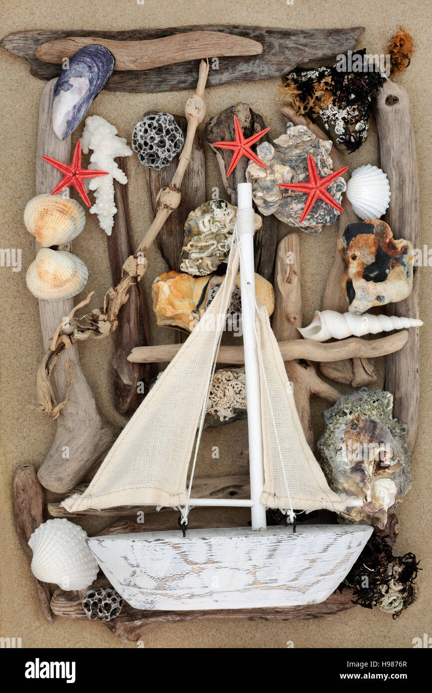 Bateau à voile décoratif sur fond abstrait avec des coquillages, du bois flotté, des rochers et des algues sur le sable. Banque D'Images