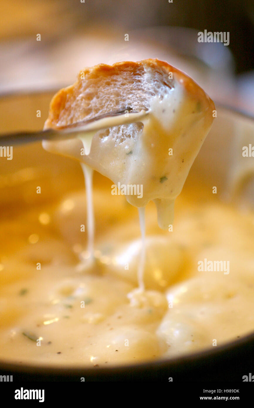 Fondue au fromage - un morceau de pain en croûtons de fromage d'un liquide Banque D'Images